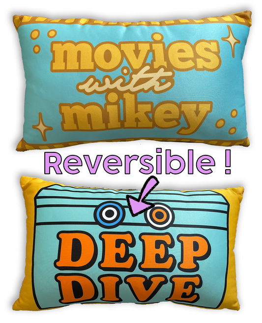 A reversible rectangle throw pillow. Both sides of pillow are shown. One with the Deep Dive box and the other size with the Movies with Mikey logo.